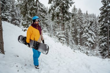 Kış sporu ve eğlence, boş zaman aktiviteleri. Güvenlik gözlüğü takan kayak ekipmanlı bir adam. Snowboardcu dağda yürüyüş yapıyor..