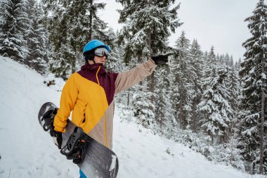 Kış sporu ve eğlence, boş zaman aktiviteleri. Güvenlik gözlüğü takan kayak ekipmanlı bir adam. Snowboardcu dağda yürüyüş yapıyor.