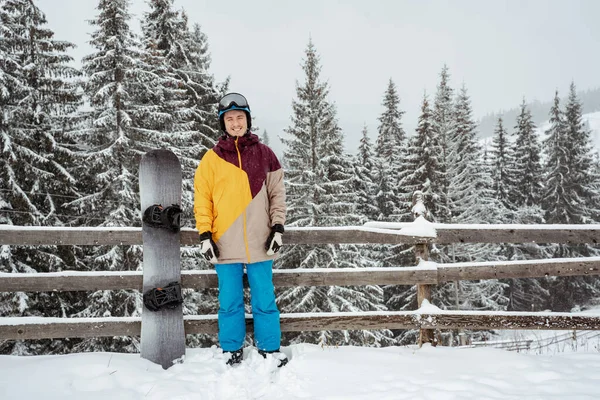 Homem em equipamento de esqui, usando óculos de segurança, fica contra a montanha e as árvores. Esportes de inverno e recreação, lazer atividades ao ar livre — Fotografia de Stock