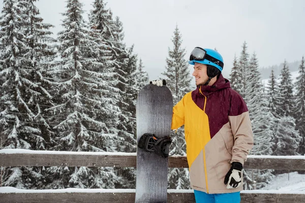 Homem em equipamento de esqui, usando óculos de segurança, fica contra a montanha e as árvores. Esportes de inverno e recreação, lazer atividades ao ar livre — Fotografia de Stock