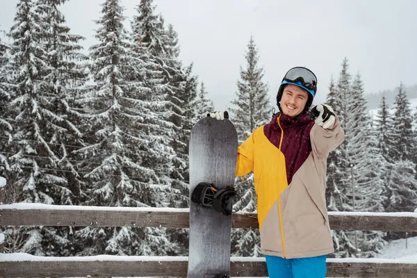 Homem em equipamento de esqui, usando óculos de segurança, fica contra a montanha e as árvores. Esportes de inverno e recreação, lazer atividades ao ar livre — Fotografia de Stock