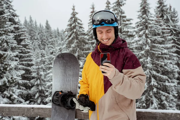 Vinter sport og rekreation, fritid udendørs aktiviteter. Mand i skiudstyr, iført sikkerhedsbriller, taler i telefon. Snowboarder mand vandreture på bjerget - Stock-foto