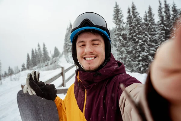 Desporto de inverno e recreação, lazer atividades ao ar livre. Homem de equipamento de esqui, com óculos de segurança, a fazer selfie. Homem de snowboarder caminhadas na montanha — Fotografia de Stock