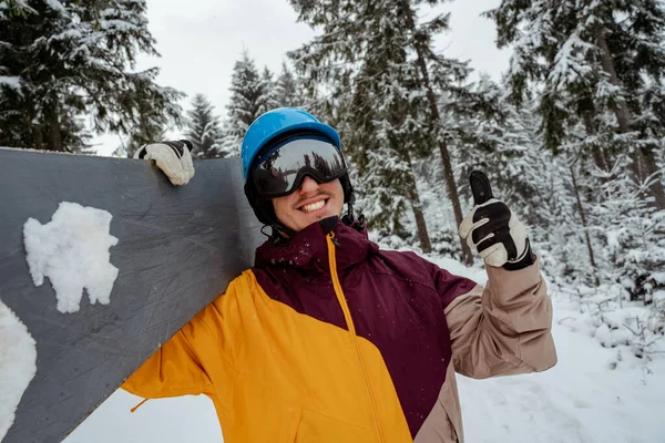 Sporty zimowe i rekreacja, rekreacja na świeżym powietrzu. Facet w sprzęcie narciarskim, w okularach ochronnych. Snowboarder człowiek wędrówki w górach — Zdjęcie stockowe