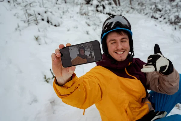 Aventura para o esporte de inverno. Homem de snowboard caminhando na montanha e fazendo selfie. À procura de pó para freeride — Fotografia de Stock