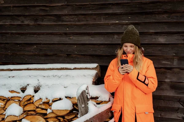 Hermosa chica sonriendo snowboarder de pie solo con el teléfono en las manos. Montaña al aire libre, actividad deportiva de invierno Imagen De Stock