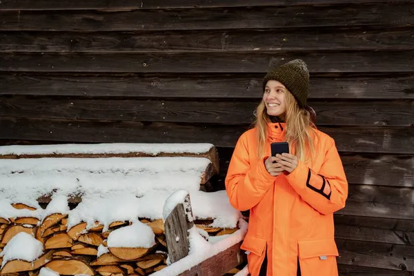 Hermosa chica sonriendo snowboarder de pie solo con el teléfono en las manos. Montaña al aire libre, actividad deportiva de invierno. Imágenes De Stock Sin Royalties Gratis