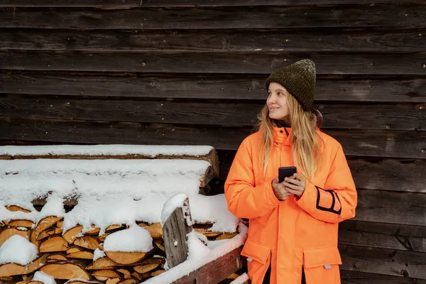 Hermosa chica snowboarder de pie solo con el teléfono en las manos. Montaña al aire libre, actividad deportiva de invierno. Fotos De Stock