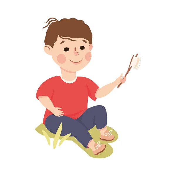 Malý chlapec sedí na zeleném trávníku se Skewered Fried Marshmallow Vector Illustration — Stockový vektor