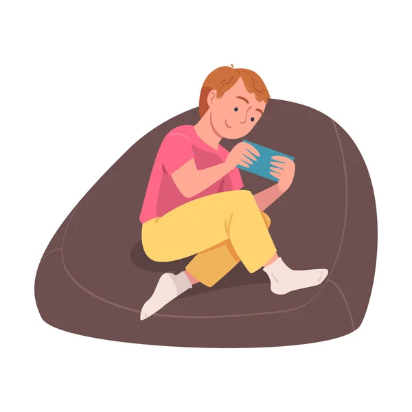 Teen chlapec postava s digitálním zařízením sedí v křesle trpí Internet závislost vektorové ilustrace — Stockový vektor