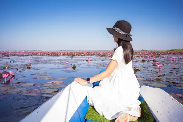 Kızıl Lotus Denizi 'nde mavi uzun bir teknede Asyalı turist kadın. Tayland, Tayland, Udon Thani Eyaleti ve Tayland 'da görülmedi..