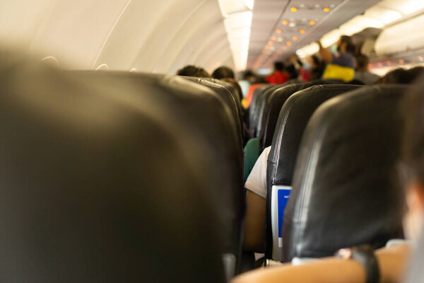 Blur passengers on the plane, some tourists are in chairs and some are packing their bags on the plane.