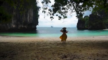 Sarı elbiseli ve şapkalı Asyalı kadın turist Hong Adası 'nda yürüyor, beyaz kumsal, Tayland, Krabi' de deniz..