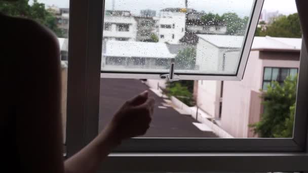 コンドミニアムの窓を閉める女外部のガラスに雨滴都市の背景の家の屋根 — ストック動画