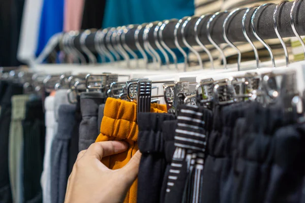 Shopper in clothing store, Clothes hang on a shelf.