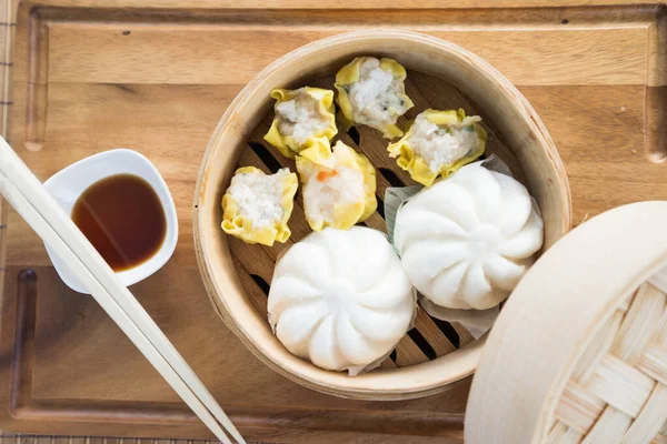 Chinese steamed pork bun and dim sumis ready to eat on serving plate and steamer.