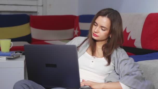 Молодая женщина сидит в комнате за компьютером, просматривая ленту новостей. Досуг. — стоковое видео