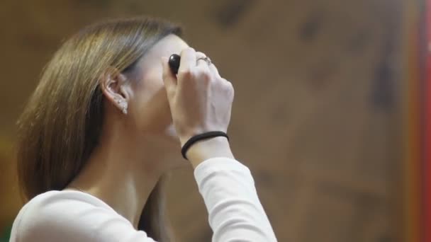 Sidovy av en kvinna som använder pulver med en sminkborste framför en spegel, en lycklig kvinna som använder kosmetika för skönhet — Stockvideo