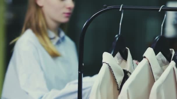 Une jolie fille choisit des vêtements dans un magasin. Shopping — Video