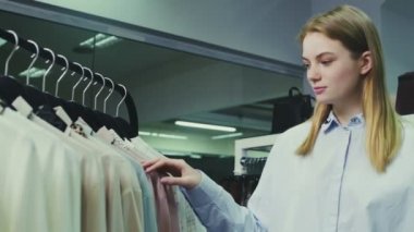 Şirin bir kız mağazadan kıyafet seçer. Alışveriş.