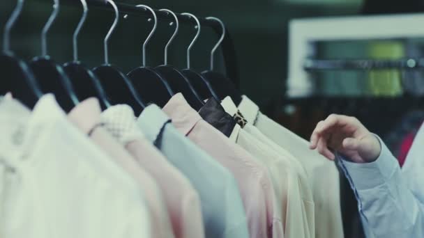 Uma menina bonito escolhe roupas em uma loja. Compras. Close-up — Vídeo de Stock