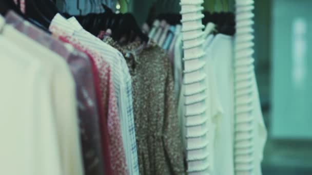 Симпатичная девушка выбирает одежду в магазине. Шопинг — стоковое видео