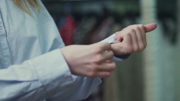 Γυναικεία χέρια κουμπώνουν τα κουμπιά στο μανίκι μιας μπλούζας, κοντινό πλάνο — Αρχείο Βίντεο