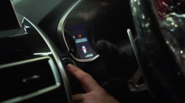 Araçların ateşlemesini açıyorum. Adam arabanın motorundaki başlatma tuşuna basıyor. Aracın kullanıma hazır işlevsel sistemlerini açıyorum. Yakın plan.