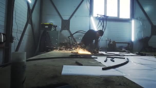 Bir adam dairesel testere ile çalışır. Sıcak metalden kıvılcımlar çıkıyor. Adam çelik üzerinde çok çalıştı.. — Stok video