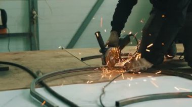 Dairesel testere ile çalışan bir adamın eli. Sıcak metalden kıvılcımlar çıkıyor. Adam çelik üzerinde sıkı çalışıyordu..