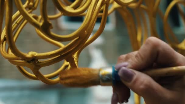 Ένα γυναικείο χέρι ζωγραφίζει μεταλλικά προϊόντα με χρυσό χρώμα, close-up — Αρχείο Βίντεο