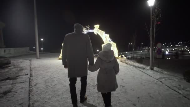 Mężczyzna i dziewczyna idą zimą do świetlanego łuku z jeleniem.. — Wideo stockowe