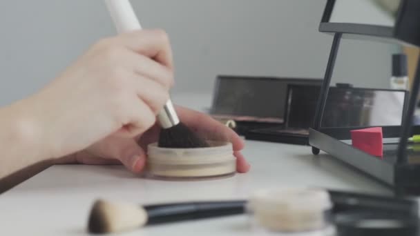 Hjem skønhedssalon. Et nærbillede af en uigenkendelig kvindelig hånd, der påfører pulver til en børste og laver daglig makeup derhjemme – Stock-video
