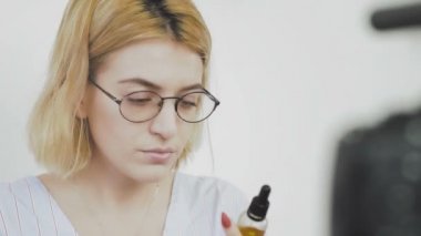 Gözlüklü, gülümseyen ve kameraya yeni bir alışveriş hakkında konuşan genç bir kadının yakın çekimi. Kişisel bakım için kozmetik incelemesi