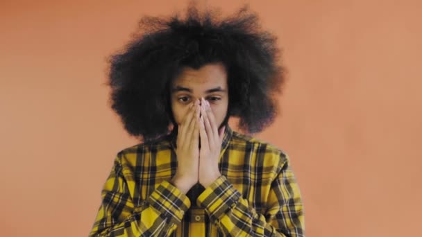 Un jeune homme avec une coiffure africaine sur fond orange est surpris. Émotions sur un fond coloré. — Video