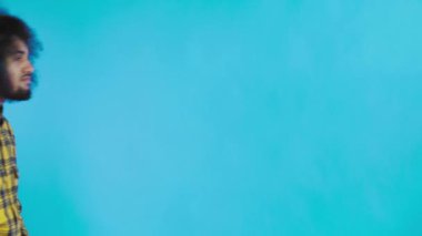 Mavi arka planda Afrikalı saç stili olan genç bir adam telefonunu çıkardı, mesaja baktı ve cebine geri koydu. Renkli bir arkaplanda duygular