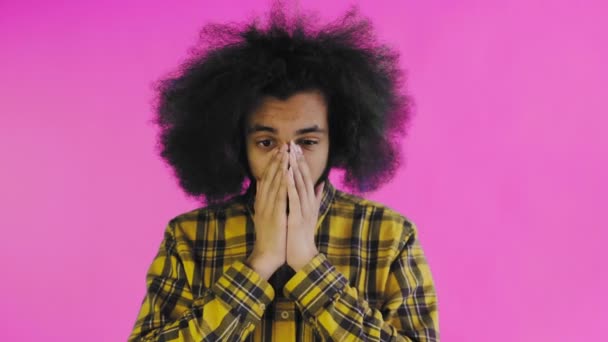 Egy afrikai frizurájú, rózsaszín hátterű fiatalember meglepődött. Érzelmek egy színes háttér. — Stock videók