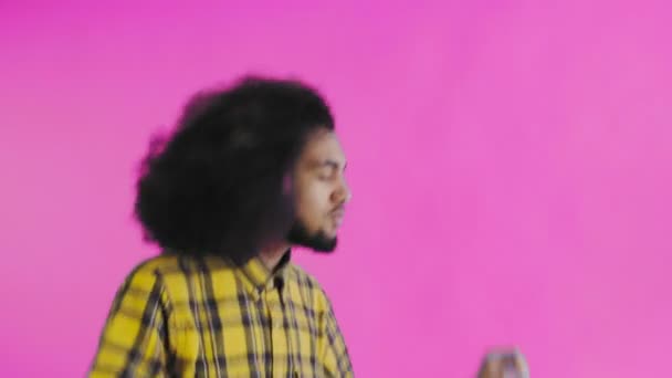Un giovane con un'acconciatura africana su sfondo rosa sta ballando. Ballando su uno sfondo colorato. — Video Stock
