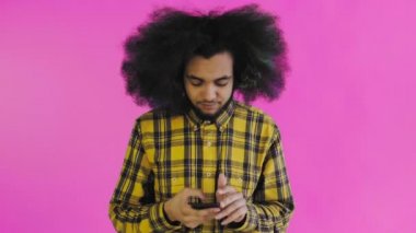 Pembe arka planda Afrikalı saç stili olan genç bir adam telefonunu çıkardı ama işe yaramadı. Renkli bir arkaplanda duygular