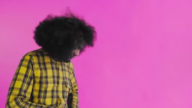 Pembe arka planda Afrikalı saç stili olan genç bir adam telefonunu çıkardı, mesaja baktı ve cebine geri koydu. Renkli bir arkaplanda duygular