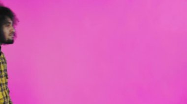 Pembe arka planda Afrikalı saç stili olan genç bir adam telefonunu çıkardı, mesaja baktı ve cebine geri koydu. Renkli bir arkaplanda duygular