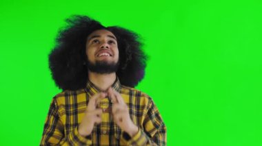 Yeşil arka planda Afrikalı saç stili olan genç bir adam dua ediyor. Renkli bir arkaplanda duygular.