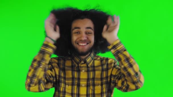 Ein junger Mann mit afrikanischer Frisur auf grünem Hintergrund ist glücklich. Emotionen auf farbigem Hintergrund. — Stockvideo