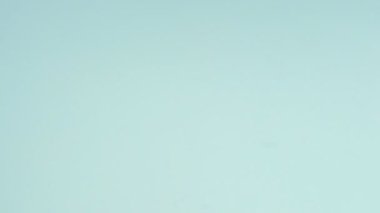 Çok renkli kurabiyelerin üst görüntüsü pastel mavi arka planda Fransız makarnaları. Bir kadının eli kurabiyeyi ortaya taşır..