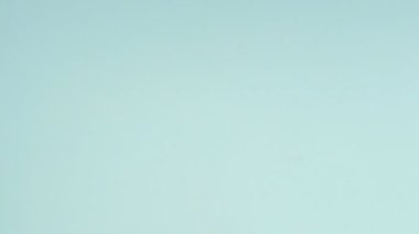 Çok renkli kurabiyelerin üst görüntüsü pastel mavi arka planda Fransız makarnaları. Bir kadının eli kurabiyeyi ortaya taşır..