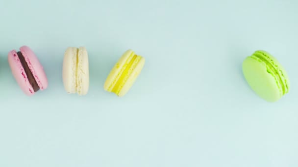 Vista superior de galletas de macarrones franceses multicolores y una taza de café sobre un fondo azul pastel — Vídeo de stock