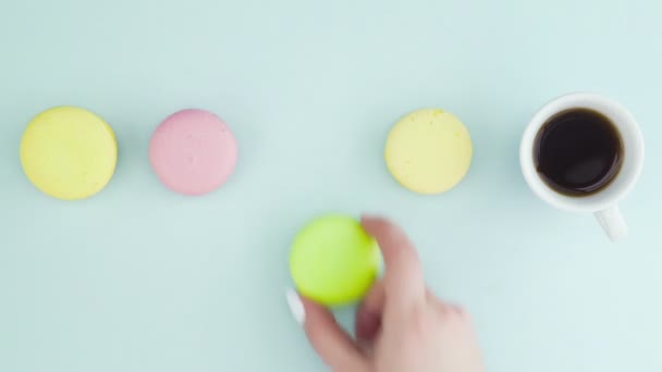 Draufsicht auf bunte französische Macarons-Kekse und eine Tasse Kaffee auf pastellblauem Hintergrund — Stockvideo
