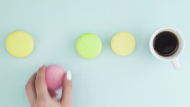 Ovanifrån av flerfärgade franska Macarons cookies och en kopp kaffe på en pastell blå bakgrund — Stockvideo