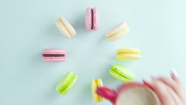 Vista superior de galletas de macarrones franceses multicolores y una taza de café sobre un fondo azul pastel — Vídeo de stock