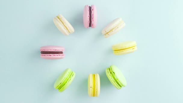 Ovanifrån av flerfärgade franska Macarons cookies och en kopp kaffe på en pastell blå bakgrund — Stockvideo